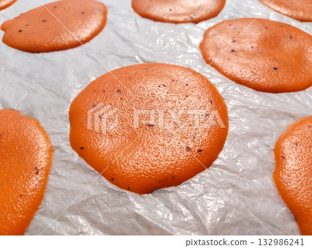 Spoon spreading small circular suji papad portions on plastic sheet for sun drying, traditional Indian snack preparation method in rural setting Spoon spreading small circular suji papad portions on plastic sheet for sun drying, traditional Indian snack preparation method in rural setting 132986241