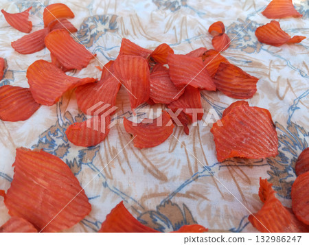 Sun-drying steamed spiced potato chips on cloth under open sky in rural India during traditional food preservation process Sun-drying steamed spiced potato chips on cloth under open sky in rural India during traditional food preservation process 132986247