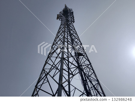 mobile network tower captured from base, showcasing steel lattice structure and signal transmission equipment against the sky, symbol of modern telecommunication infrastructure 132986248