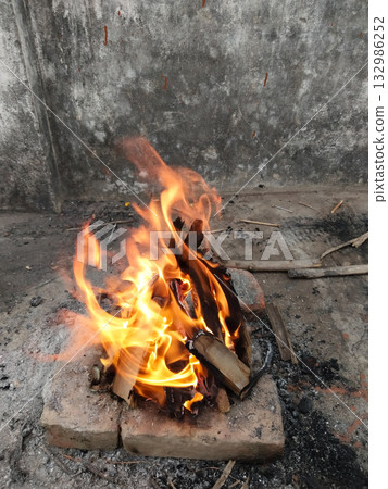 Burning wooden sticks during winter season for warmth in rural area, traditional method to create heat using small fire from dry wood pieces for surviving cold night in countryside 132986252