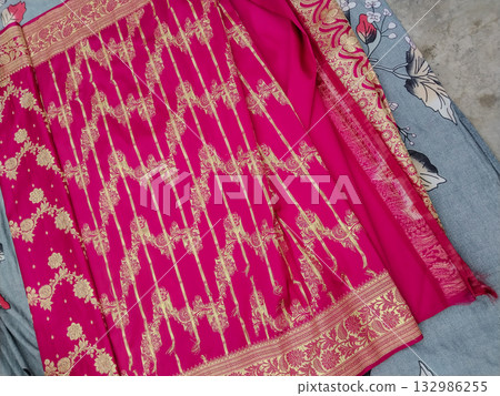 Traditional Indian ethnic fabric with golden embroidery on pink cloth bridal dress material with intricate zari design and floral patterns for saree or salwar kameez. 132986255