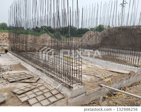 Side view of canal bridge construction site showing reinforced steel bars, concrete shuttering, and deep foundation trenches as part of large-scale civil engineering and infrastructure project 132986256