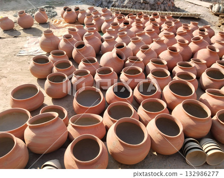 Multiple traditional earthen pots (handi) arranged on the ground for drying under the sun, symbolizing rural craftsmanship and pottery culture in Indian villages. Multiple traditional earthen pots (handi) arranged on the ground for drying under the sun, symbolizing rural craftsmanship and pottery culture in Indian villages. 132986277
