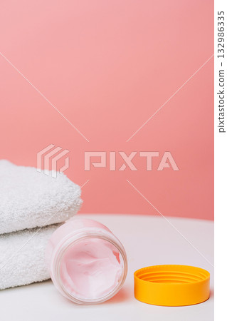 Open pink cream jar with yellow lid and towel Open pink cream jar with yellow lid and towel 132986335