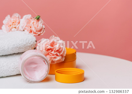 Pink moisturizer jar with carnations and towels Pink moisturizer jar with carnations and towels 132986337