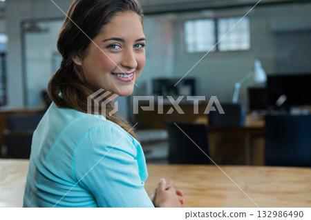 Woman smiling while typing on keyboard at table in loft office with monitors, copy space 132986490