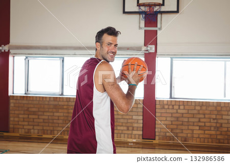 Male basketball player in jersey holding ball preparing shot in gym under hoop and net 132986586