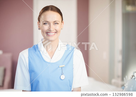 Female nurse smiling near bedside table in hospital room with badge, fob watch and medical device Female nurse smiling near bedside table in hospital room with badge, fob watch and medical device 132986598