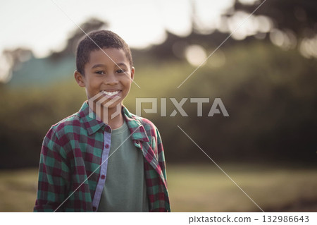 African American boy standing in grassy field smiling and wearing green t-shirt and plaid shirt African American boy standing in grassy field smiling and wearing green t-shirt and plaid shirt 132986643