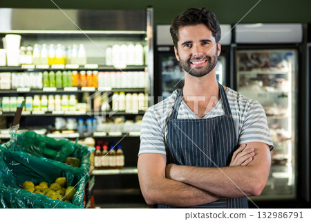 Male clerk wearing striped apron sorting yellow pears in grocery store by fridge cases, copy space Male clerk wearing striped apron sorting yellow pears in grocery store by fridge cases, copy space 132986791