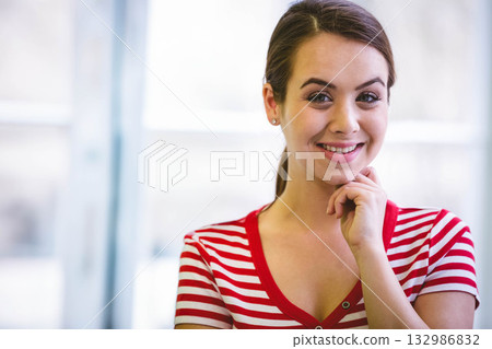 Woman smiling and resting chin on hand in bright room with large windows, copy space Woman smiling and resting chin on hand in bright room with large windows, copy space 132986832