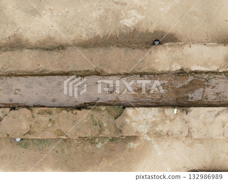 Small drainage channel made with red bricks in rural setting showing simple village water management system and traditional handmade drainage structure on earthy ground Small drainage channel made with red bricks in rural setting showing simple village water management system and traditional handmade drainage structure on earthy ground 132986989