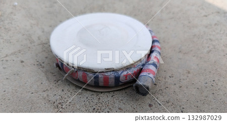 Unlit chakri firework spinners arranged on ground surface for celebration, traditional Indian fireworks display preparation with colorful circular crackers before ignition Unlit chakri firework spinners arranged on ground surface for celebration, traditional Indian fireworks display preparation with colorful circular crackers before ignition 132987029