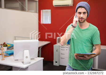 Man making phone call while holding stack of folders at office desk with monitor, copy space Man making phone call while holding stack of folders at office desk with monitor, copy space 132987272