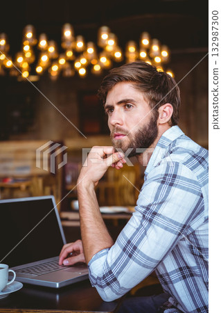 Man using laptop drinking coffee at wooden table in cafe with chandelier lights, copy space Man using laptop drinking coffee at wooden table in cafe with chandelier lights, copy space 132987300