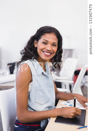 Woman wearing denim top drawing on digital tablet using stylus pen at desk in modern office Woman wearing denim top drawing on digital tablet using stylus pen at desk in modern office 132987479