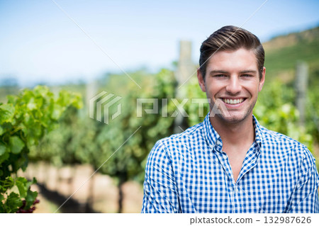 Man standing among grape vines and vine posts in vineyard under clear sky, copy space Man standing among grape vines and vine posts in vineyard under clear sky, copy space 132987626