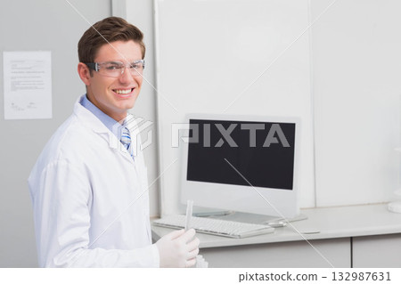 Male scientist holding test tube near workstation wall displays wearing protective gear, copy space 132987631