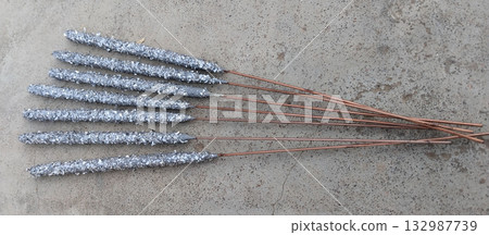 Close-up of multiple unused Diwali sparklers scattered on ground surface, unboxed fireworks with colorful sticks lying on floor before use during Indian festive preparation scene 132987739