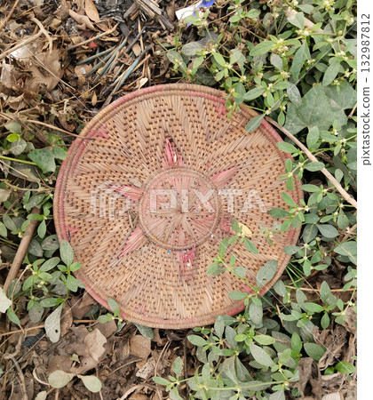 Woven bamboo basket discarded in garbage heap showing rural waste disposal and traditional handwoven item thrown among trash in an outdoor unclean environment Woven bamboo basket discarded in garbage heap showing rural waste disposal and traditional handwoven item thrown among trash in an outdoor unclean environment 132987812