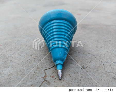 Colorful plastic lattu spinning top resting on earthy ground, representing simple childhood toy from Indian culture, nostalgic desi play item popular in rural and urban settings 132988313