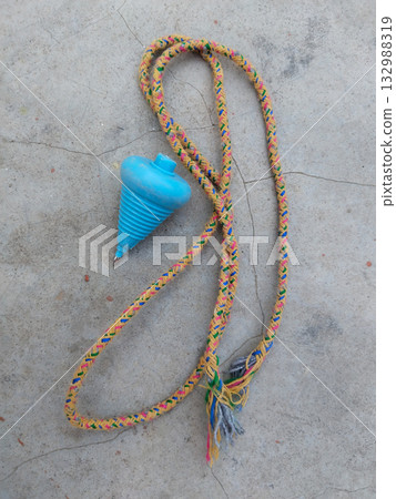 Traditional Indian lattu spinning top with attached string placed on dusty ground, representing desi childhood games, rural playtime preparation, and nostalgic moments of classic toys Traditional Indian lattu spinning top with attached string placed on dusty ground, representing desi childhood games, rural playtime preparation, and nostalgic moments of classic toys 132988319