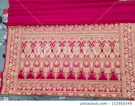 Full view of traditional Indian embroidered fabric saree with intricate floral and paisley zari design on magenta pink textile | Ethnic dress material | cloth for fashion and tailoring 132988349