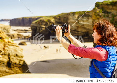 Woman with camera at Cathedral Beach in Spain. Woman with camera at Cathedral Beach in Spain. 132988759