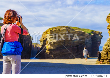 Woman with camera at Cathedral Beach in Spain. Woman with camera at Cathedral Beach in Spain. 132988761