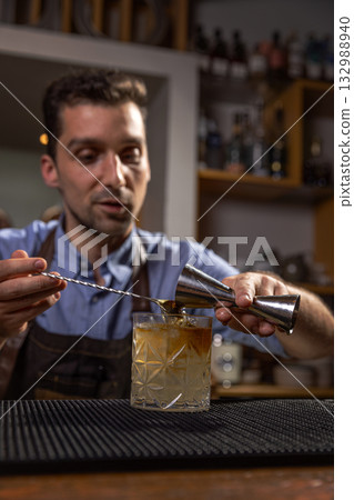 Bartender pouring liquid into cocktail glass 132988940