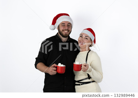 a couple is holding red mugs of a hot beverage, celebrating the Christmas season 132989446