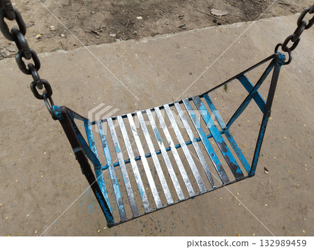 swings on metal frame in outdoor playground, surrounded by green trees, slides, and seesaws, fun recreation for children swings on metal frame in outdoor playground, surrounded by green trees, slides, and seesaws, fun recreation for children 132989459