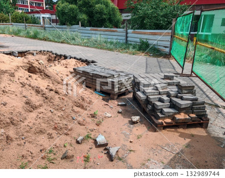 Unfinished Pavement with Exposed Sand and Displaced Bricks at Construction Site. sidewalk repair, paving stones in progress 132989744