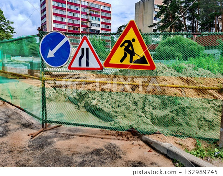 Road signs - sidewalks are being repaired and paving stones are being laid. Road work and detour signs on the city road Road signs - sidewalks are being repaired and paving stones are being laid. Road work and detour signs on the city road 132989745