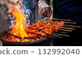 India Street Food, Street vendor grilling smoky tandoori chicken skewers over an open flame 132992040