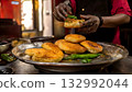 India Street Food, Vendor preparing spicy vada pav, with a side of fried green chili 132992044