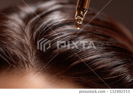 Woman applying oil drop to long shiny hair with serum dropper pipette. Hair background. Close up person takes care moisturizes head skin. Beauty caring for scalp. Alopecia problem, growth, nourishment Woman applying oil drop to long shiny hair with serum dropper pipette. Hair background. Close up person takes care moisturizes head skin. Beauty caring for scalp. Alopecia problem, growth, nourishment 132992553