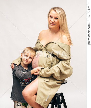 Warm family portrait of pregnant woman with her son in bright studio setting. Soft light, neutral tones and emotional connection perfect for family and maternity concepts 132994749