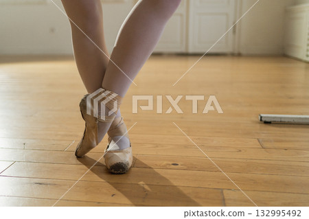 Worn ballet pointe shoes on feet in dance class. Well worn pointe shoes of ballet dancer. Classical ballerina woman in dance studio. Classical pointe shoes for dance training. Ballet school concept Worn ballet pointe shoes on feet in dance class. Well worn pointe shoes of ballet dancer. Classical ballerina woman in dance studio. Classical pointe shoes for dance training. Ballet school concept 132995492