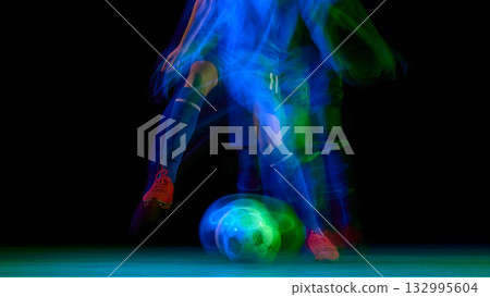 Soccer ball and player legs in motion blur with glowing green light 132995604