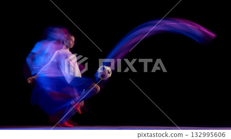 Female football player striking ball with speed and precision Female football player striking ball with speed and precision 132995606