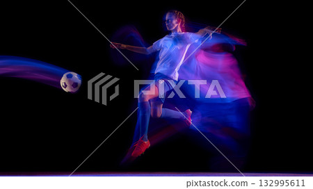 Female football player kicking ball in neon light motion. 132995611