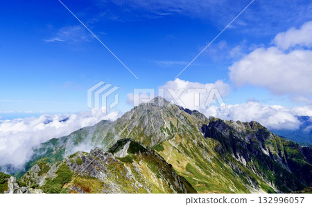 A magnificent view of Mount Tsurugi towering over a blue sky and sea of clouds - a famous peak in the Northern Alps 132996057