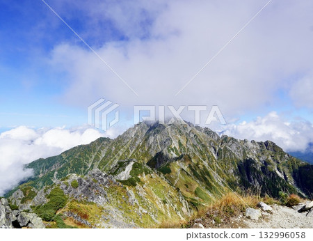 A magnificent view of Mount Tsurugi towering over a blue sky and sea of clouds - a famous peak in the Northern Alps 132996058