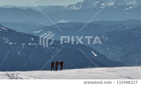 Mountaineers standing on snowy mountain ridge enjoying scenic view Mountaineers standing on snowy mountain ridge enjoying scenic view 132996227