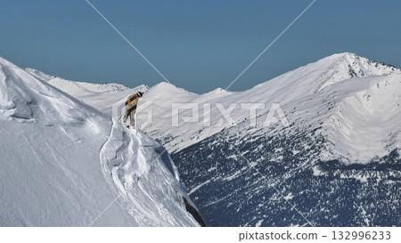 Skier evaluating snowy ridge line in mountain landscape Skier evaluating snowy ridge line in mountain landscape 132996233