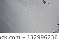 Skier leaving tracks on pristine snow field near rocky cliffs 132996236