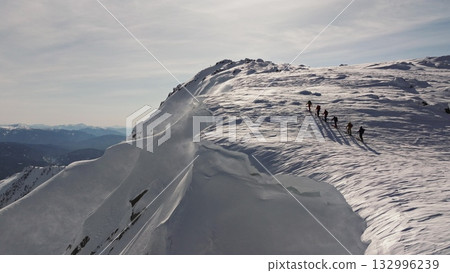 Climbers traversing snowy mountain ridge in stunning winter scenery Climbers traversing snowy mountain ridge in stunning winter scenery 132996239