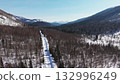 Snowy mountain road winding through serene winter landscape 132996249