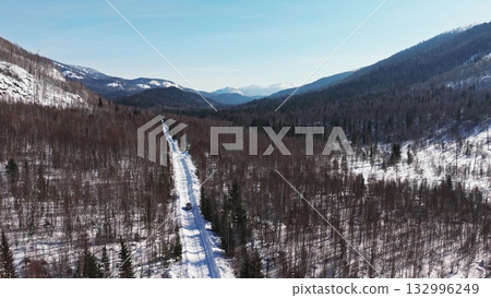 Snowy mountain road winding through serene winter landscape Snowy mountain road winding through serene winter landscape 132996249